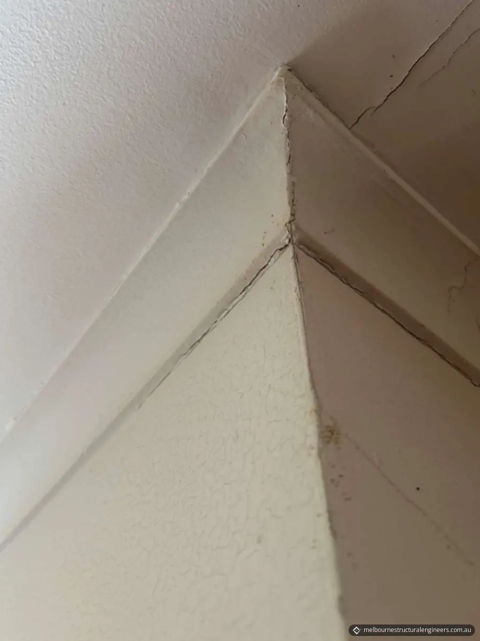 Cracked cornice mitre at a room corner, with cracks along the cornice and ceiling junctions