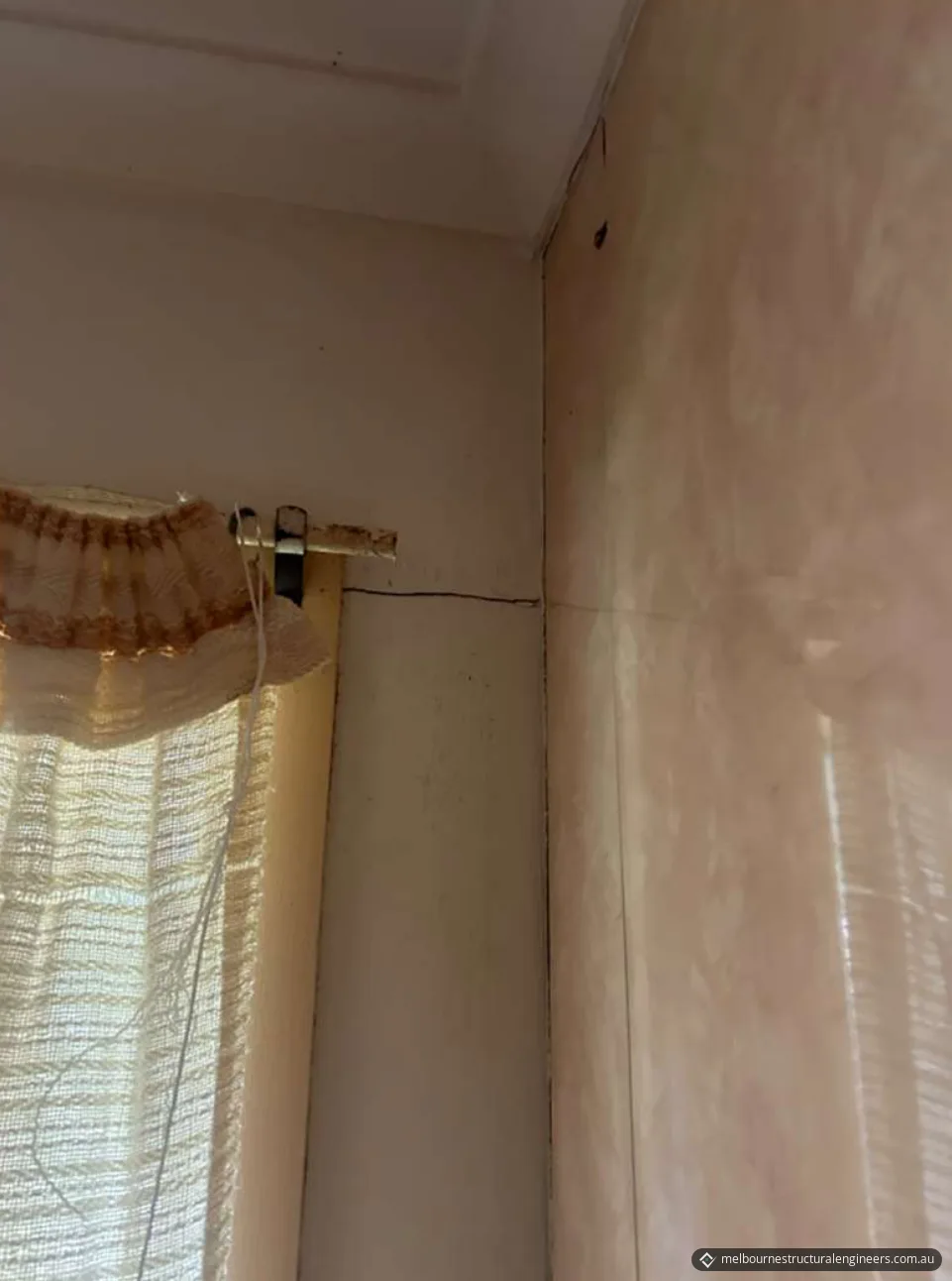 Horizontal crack running from the top of a window frame to an internal wall corner, with a vertical crack down the corner