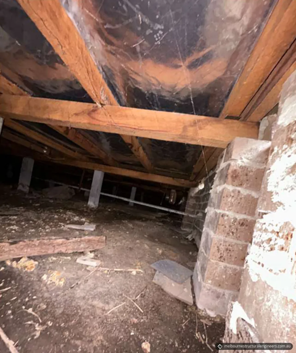 Subfloor space with timber bearers and joists on concrete stumps, next to brick masonry